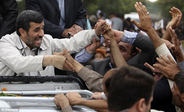 Iranian President Mahmoud Ahmadinejad shakes hands with supporters as he is welcomed to Hamadan