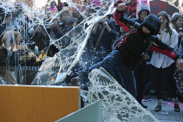 A demonstrator attempts to escape the confrontation between protesters and police, outside the entrance to Millbank Tower, housing the headquarters of the Conservative Party, during a protest in London  against an increase in university tuition fees. Organizers said 50,000 students, lecturers and supporters were demonstrating against plans to raise the cost of studying at a university to $14,000 a year - three times the current rate.