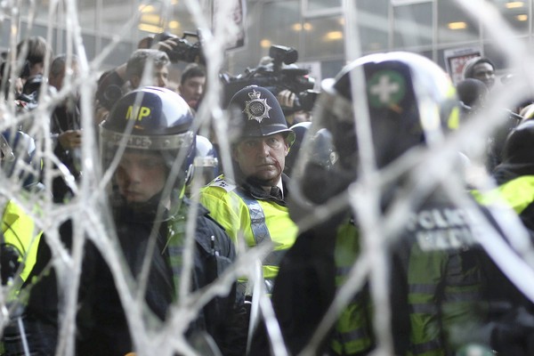 An injured police officer looks through a smashed window during clashes with student protesters as attempt to enter Millbank Tower home of Conservative Party headquarters in London. Student groups are protesting the government's proposed funding cuts to education and an increase in tuition fees.