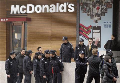 Police officers ask a journalist, lower right, to leave as he covers people gathering in front of a McDonald's restaurant which was a planned protest site in Beijing, February 20, 2011. Jittery Chinese authorities staged a concerted show of force Sunday t