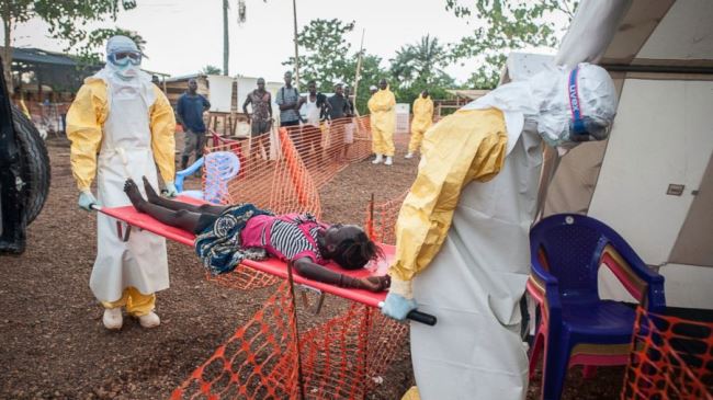 Two medical staff carrying a weak patient who has been in contact with people infected with Ebola to an Ebola Treatment Center in Liberia (file photo)