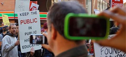 Onlookers take photographs with their phones as members of the Occupy Boston movement are joined by students from local colleges and universities demonstrating against the cost of education in downtown Boston. (photo: Brian Snyder/Reuters)