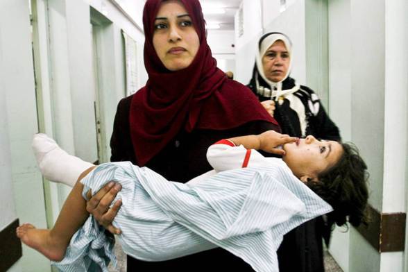 A Palestinian mother  carries her wounded daughter after an airstrike on Gaza
