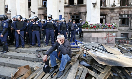 A man sits outside the trade union building where a deadly fire occurred in Odessa