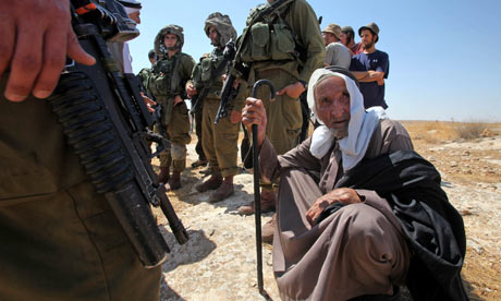 Israeli soldiers and settlers surround an elderly Palestinian man