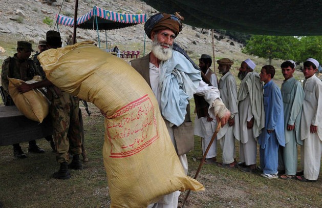An elderly displaced man carries a sack of rations on his shoulder in northern Pakistan. Credit: Ashfaq Yusufzai/IPS