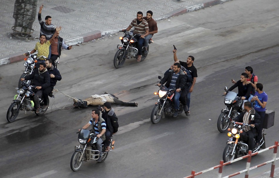 Palestinian gunmen ride motorcycles as they drag the body of a man, who was suspected of working for Israel (Reuters)