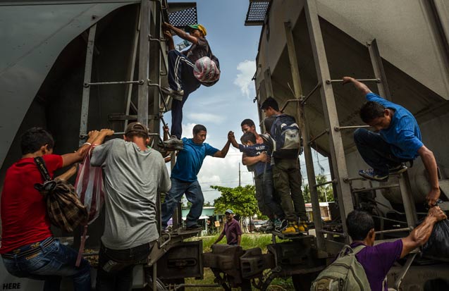 Undocumented migrants pass a boy between two cars on a moving northbound freight train known as "The Beast," because of rampant accidents and violent crime, as it passes through Tenosique, Mexico, July 2, 2014. (Photo: Meridith Kohut / The New York Times)