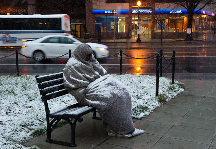 A homeless man sits covered in snow early in Washington, DC. (AFP Photo / Karen Bleier)