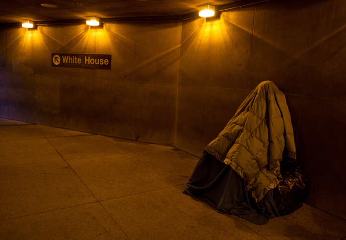 A homeless person covered in blankets for warmth, sleeps at the entrance of a Metro station near the White House in Washington, DC. (AFP Photo / Karen Bleier)