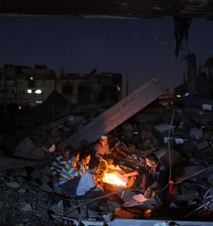 Palestinian boys sit in rubble around a fire in a house destroyed during an Israeli airstrike in Beit Lahia in the northern Gaza Strip, Nov. 26, 2012. (Photo: Wissam Nassar / The New York Times) 