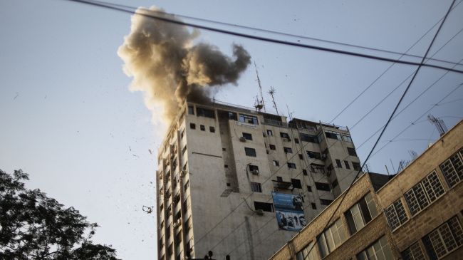 Smoke billows as debris flies from the explosion at the local Al-Aqsa TV station in Gaza City on November 18, 2012, after it was attacked during an Israeli airstrike.