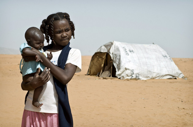 A young Sudanese girl holding a baby near a USAID tent in the Al Salam internally displaced persons camp. The United Nations Childrens Fund estimates that 33 percent of Sudanese women aged 20 to 24 were married before the age of 18. Credit: Sven Torfinn/CC By 2.0