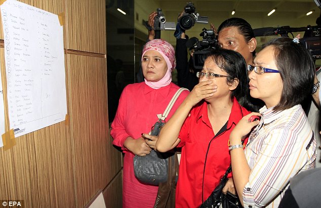 Worry: Relatives of passengers look at the list of who was on board the missing flight